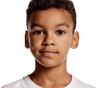 Young boy standing in front of bunk beds, looking serious, used to illustrate the emotional impact of molluscum on children.