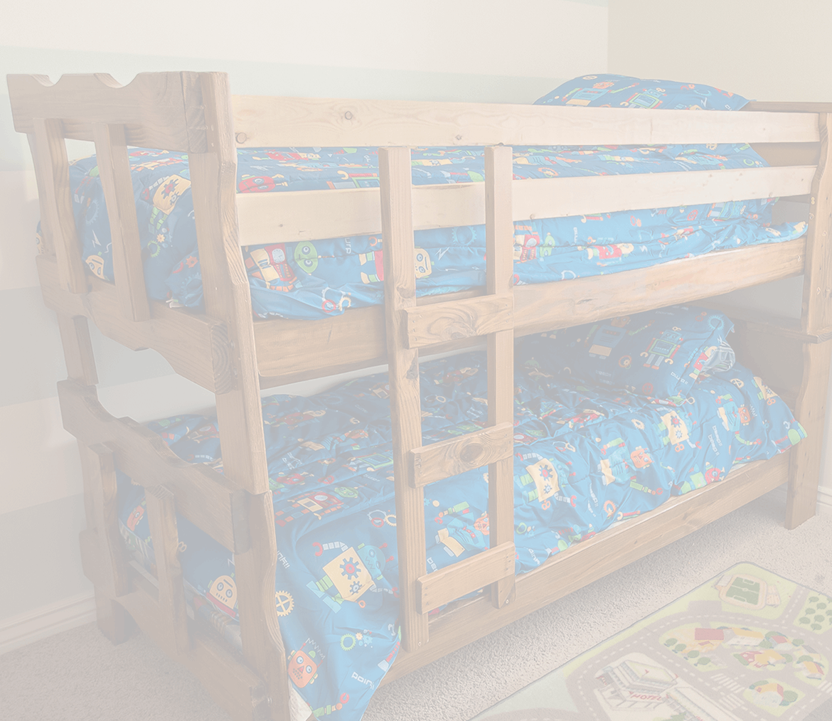 Young boy standing in front of bunk beds, looking serious, used to illustrate the emotional impact of molluscum on children.
